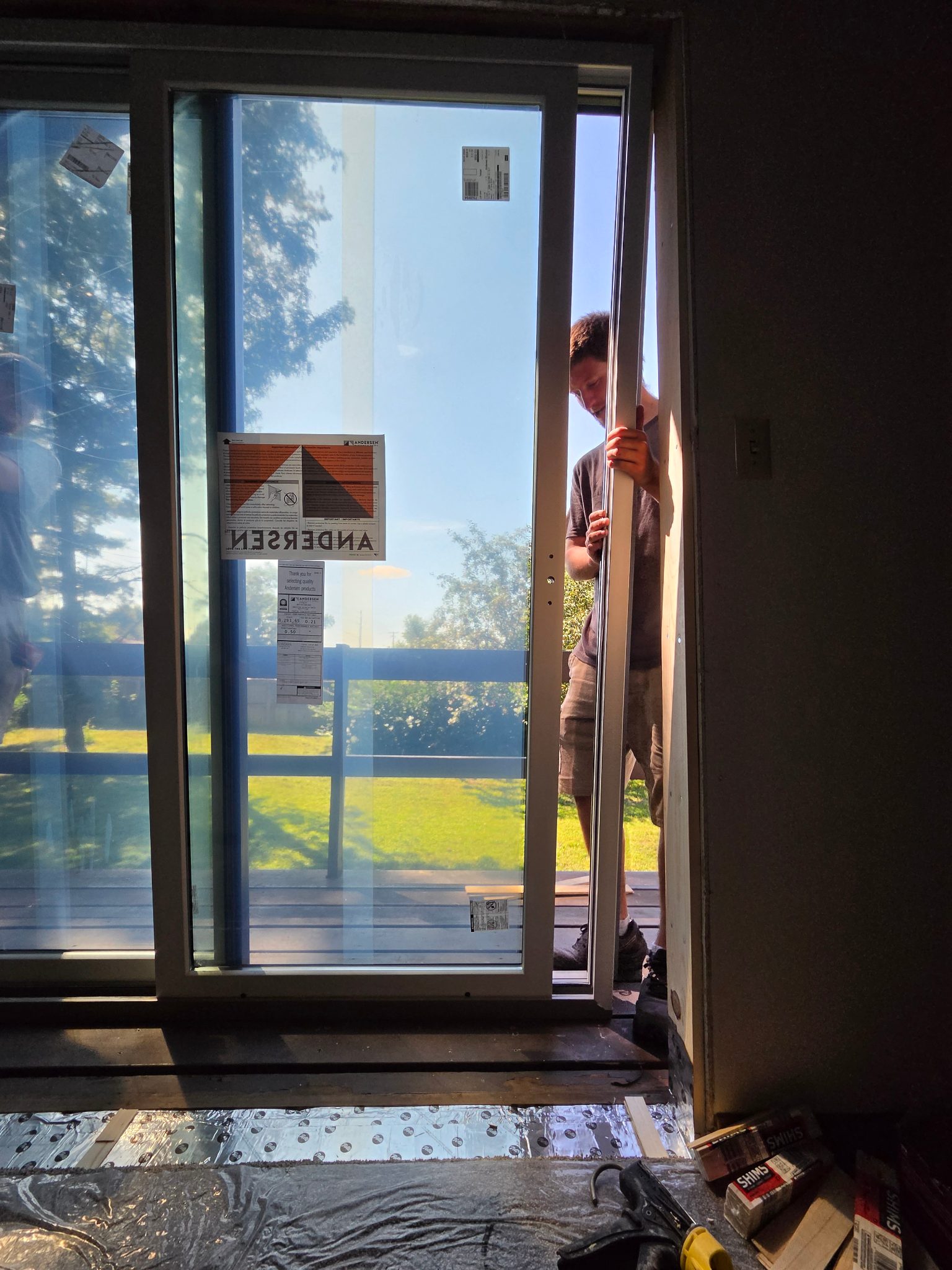 Close-up detail of a new white vinyl sliding patio door installation in Ames, showing a team member making final adjustments to the frame.