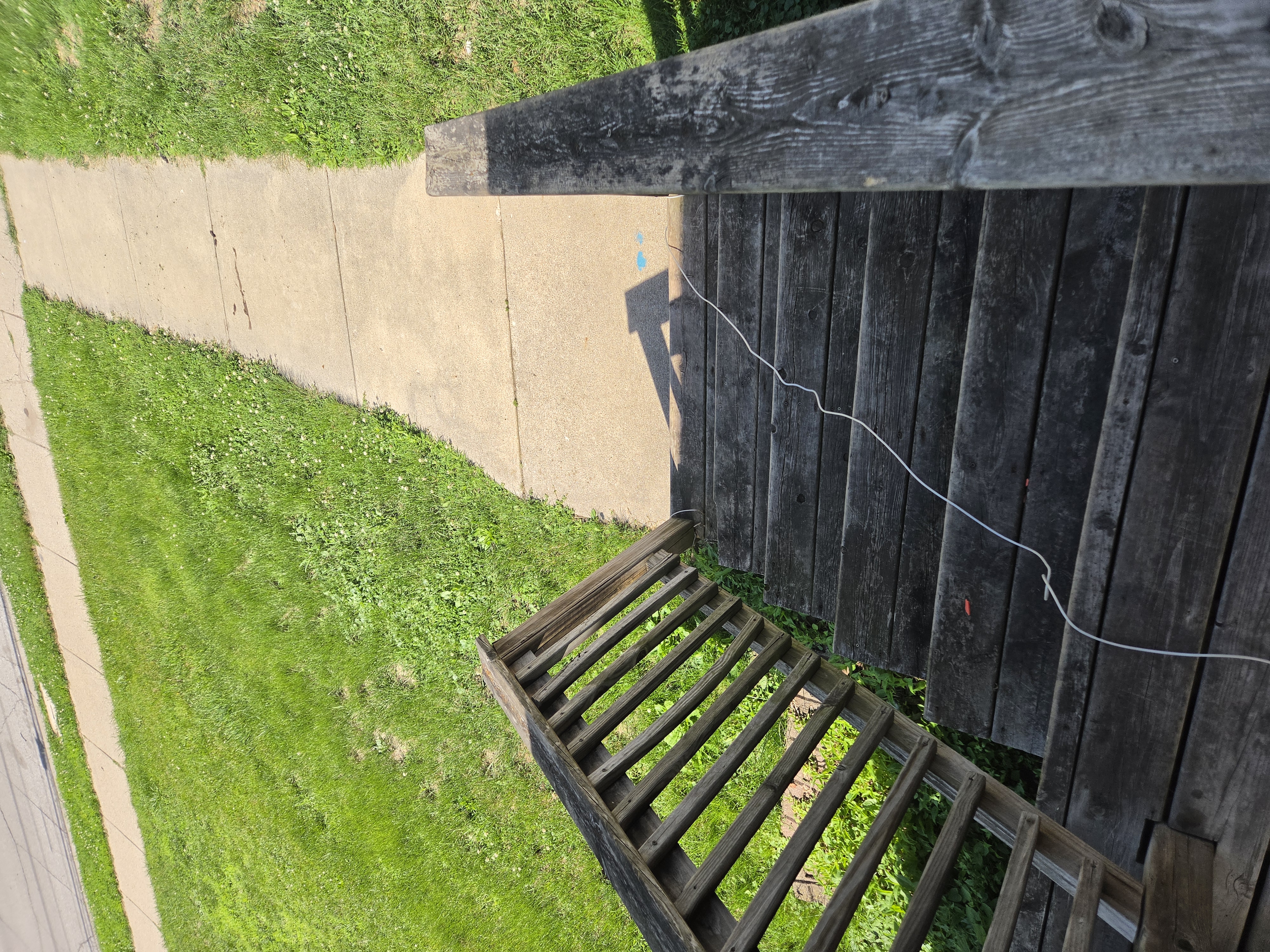 View down a set of worn wooden porch steps next to a sidewalk, Ames rental property turnover project.