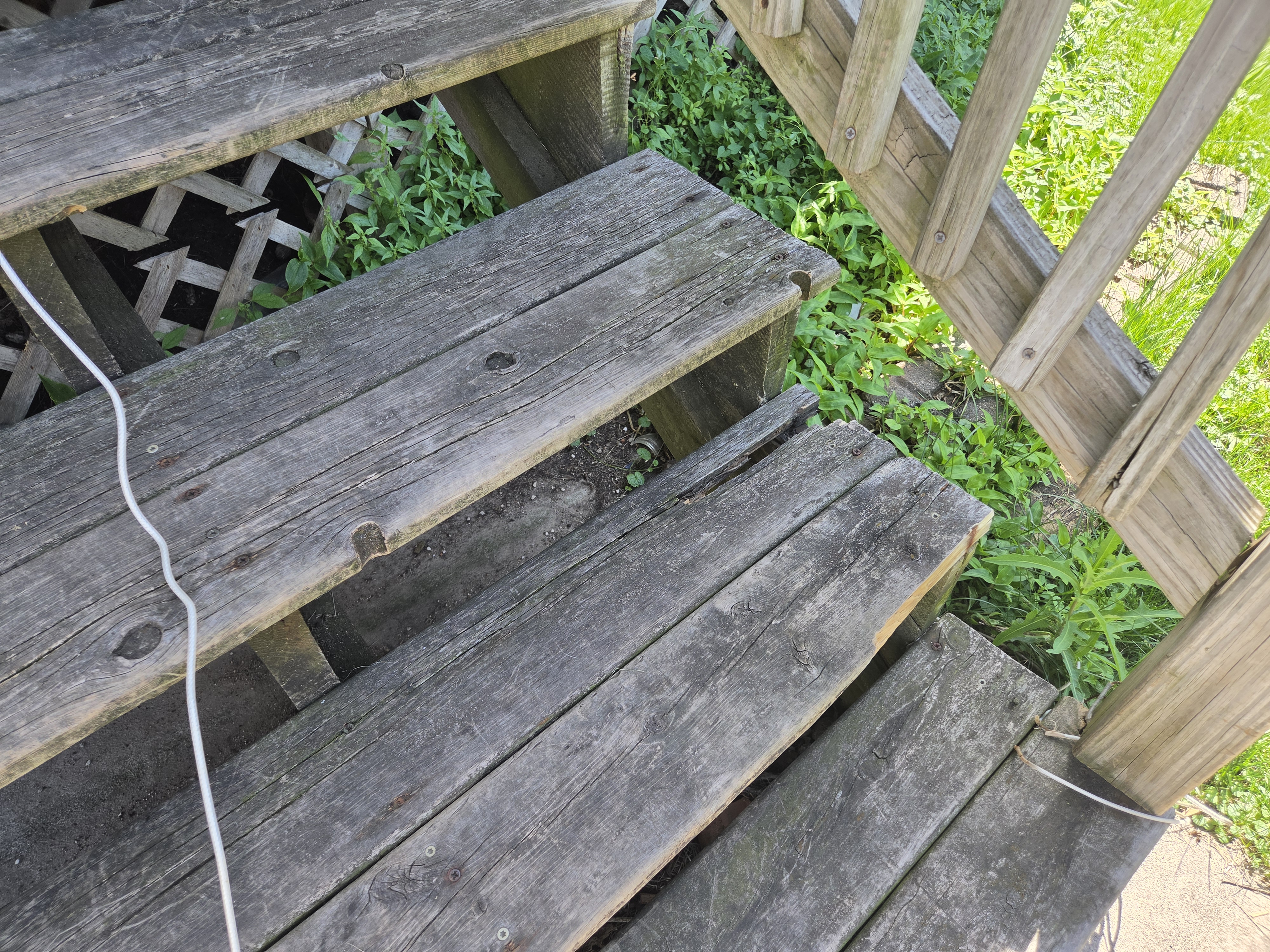Close-up of severely weathered and damaged wooden porch steps, Ames rental property turnover project.