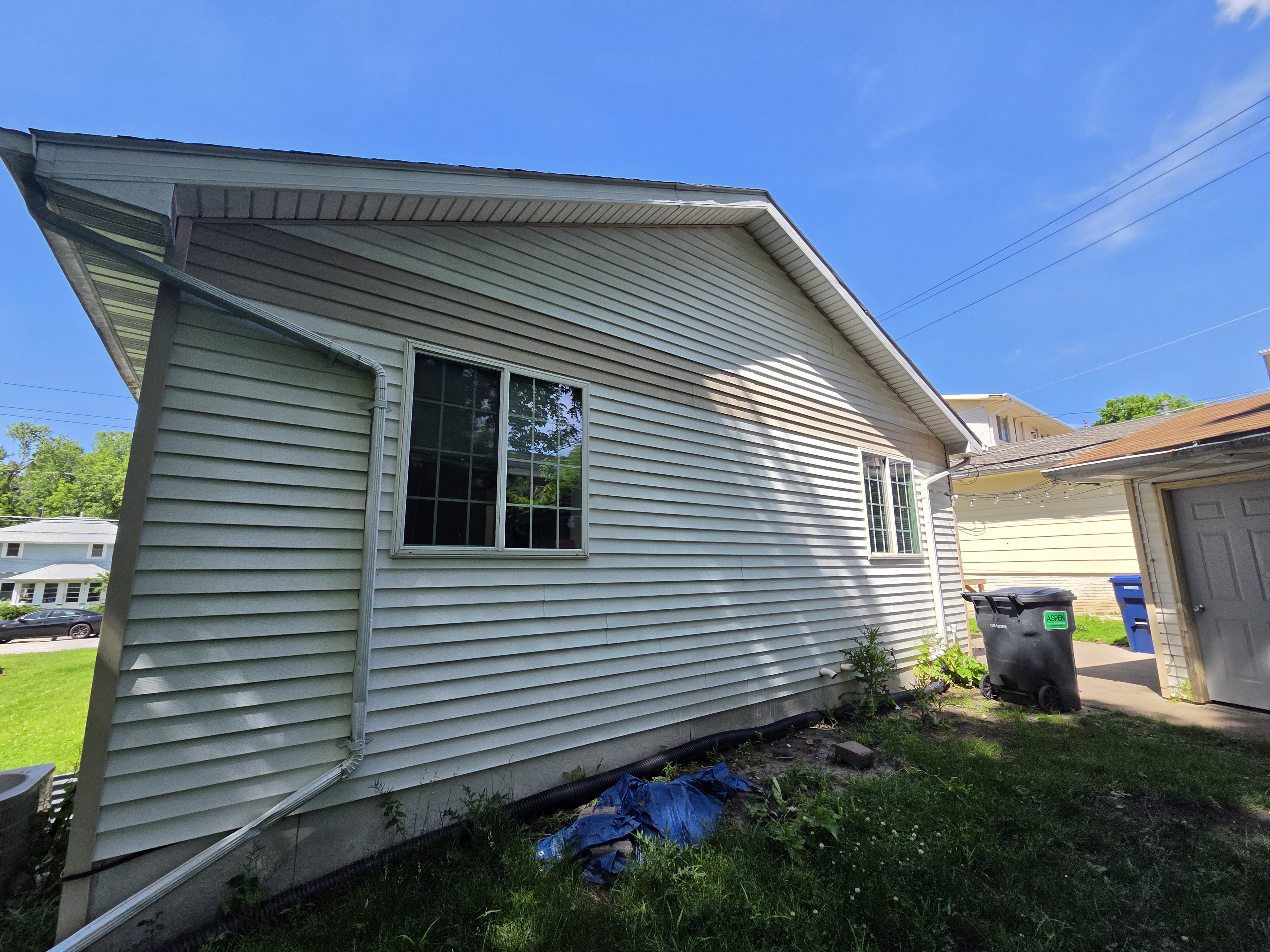 Side exterior of a house showing stained siding and a window, Ames rental property turnover project.