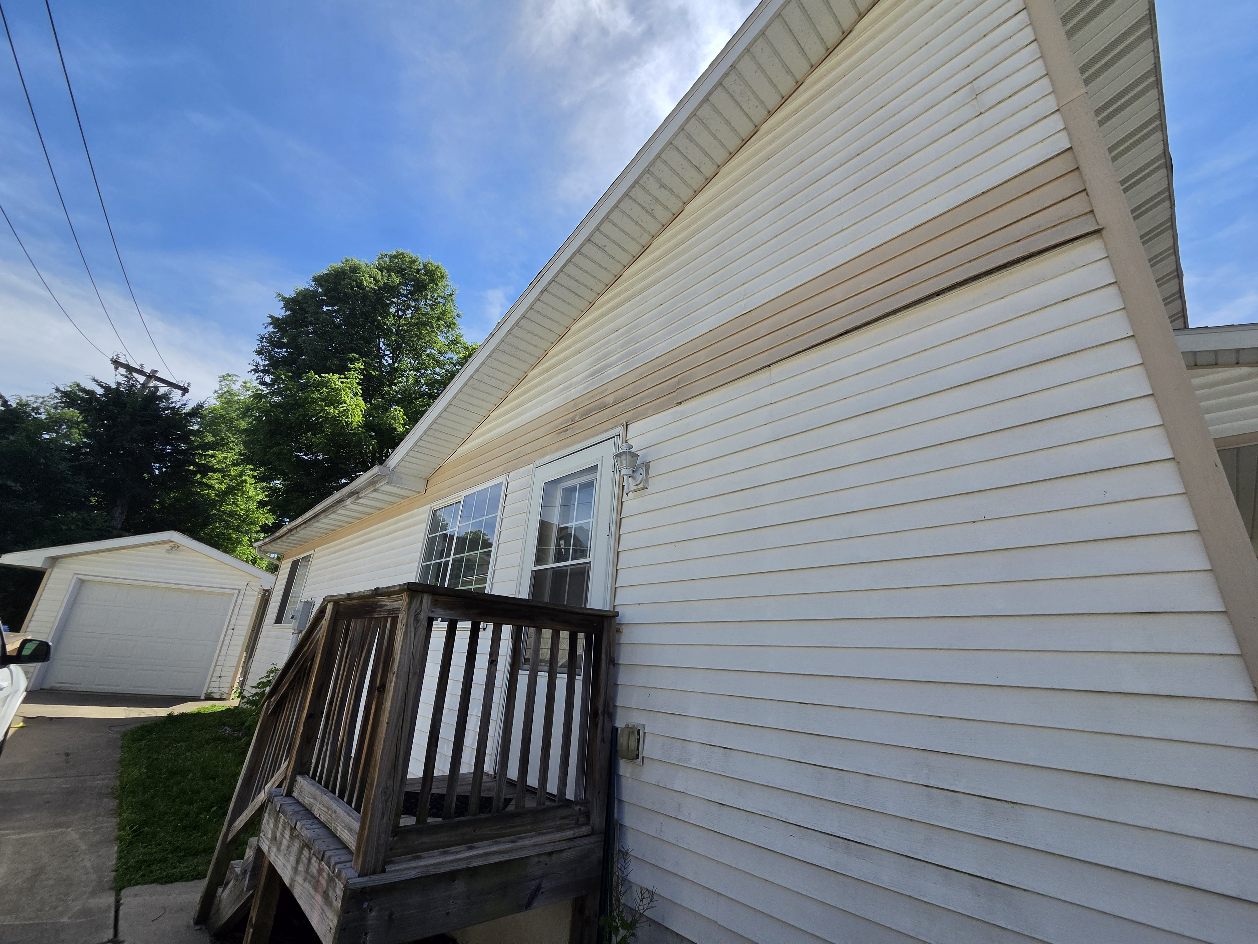 Angled view of the side and front of a house with wooden porch steps, Ames rental property turnover project.
