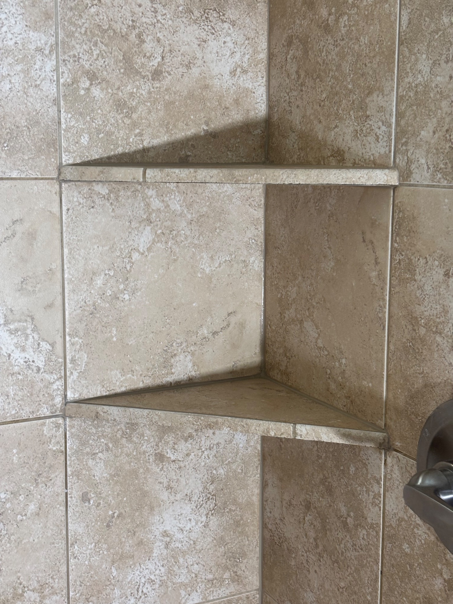 After photo of a tiled shower niche with clean caulk lines in Johnston, Iowa, after a shower grout and caulk remediation project.