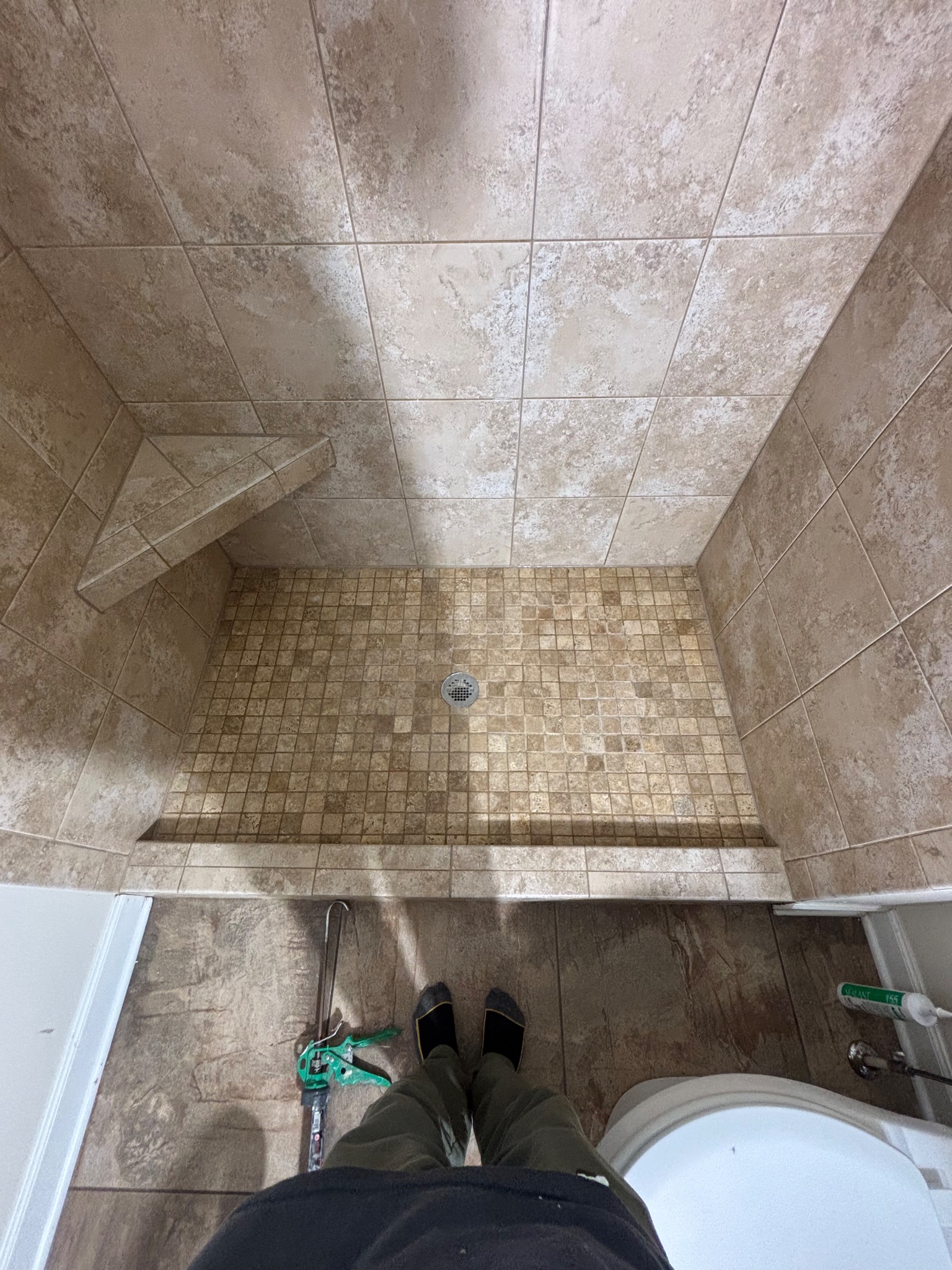 Detail photo of a clean tiled shower, looking down from above, showing a shower bench and floor in Johnston, Iowa, after a shower grout and caulk remediation project.