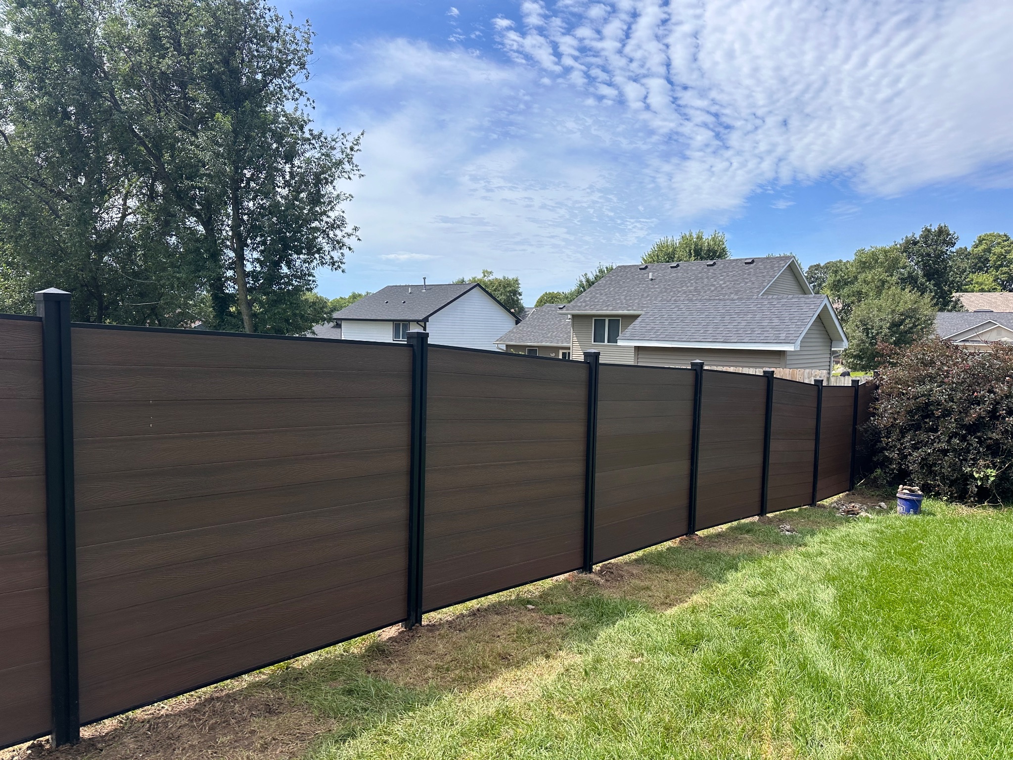 Long view of a newly installed brown composite fence in Des Moines, Iowa
