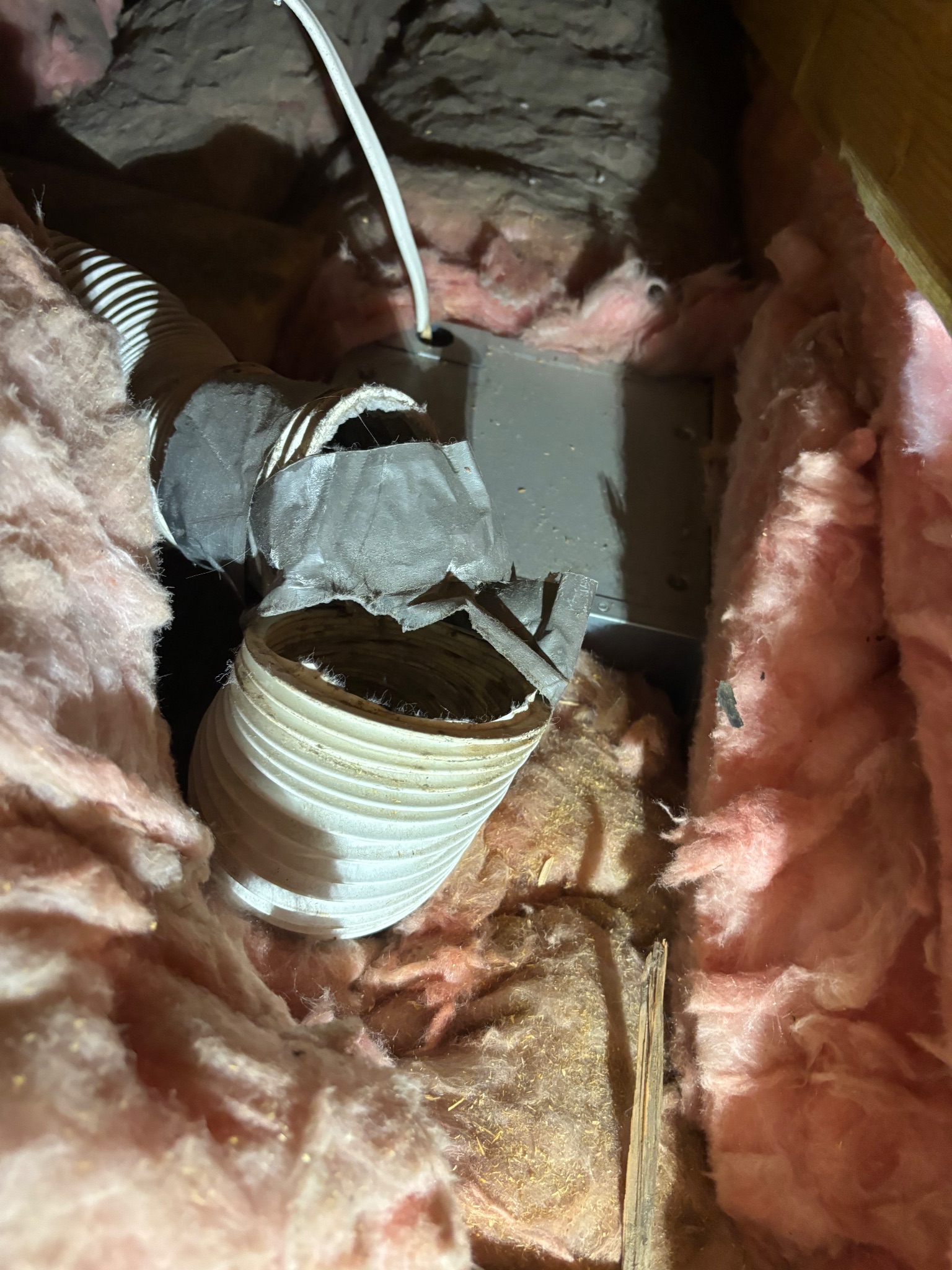 Close-up of a damaged bath fan vent line and adjacent electrical box in an attic in Ames, Iowa, before repair.