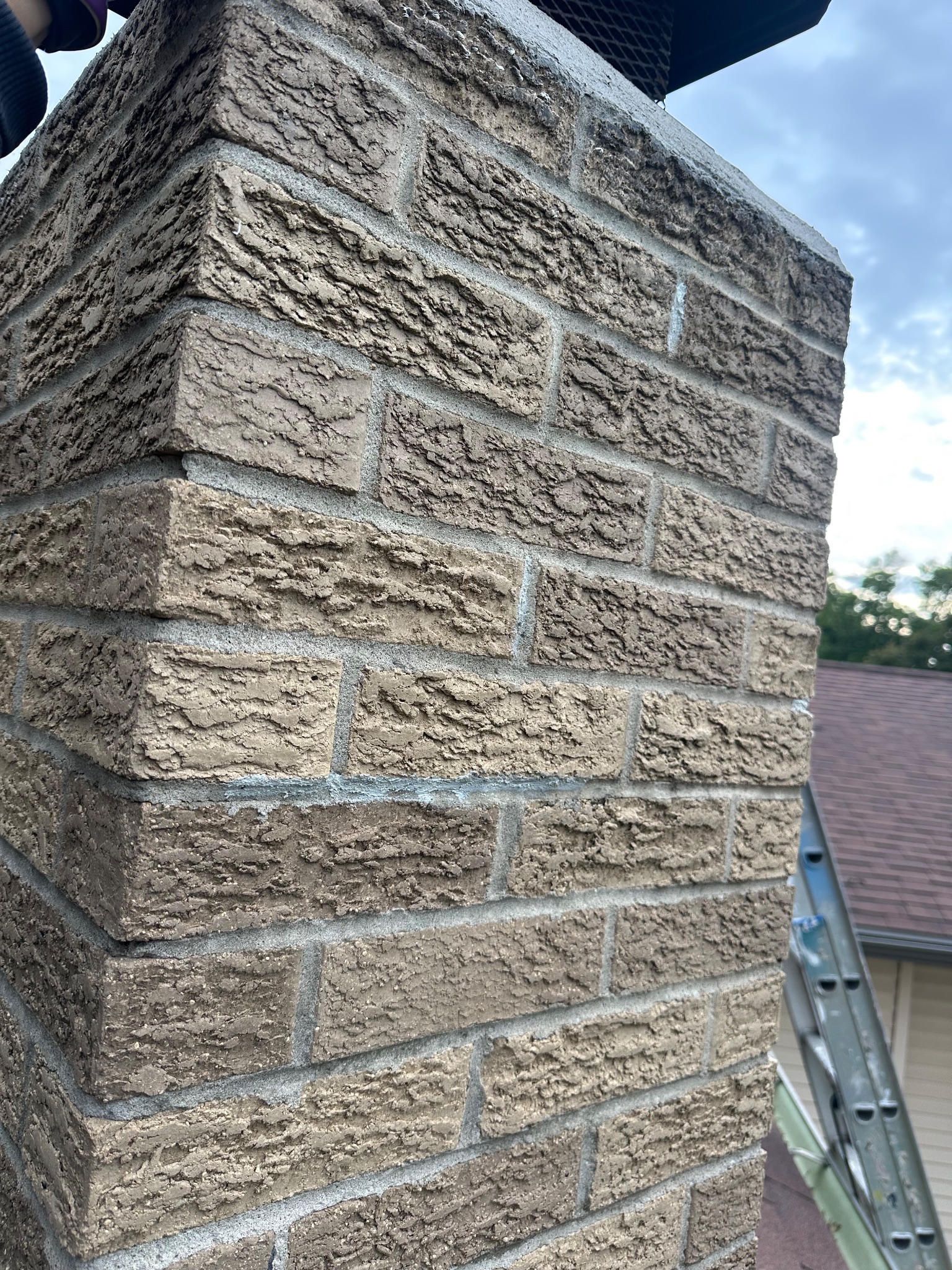 Side view of chimney with sealed mortar joints on a roof in Ames handyman project.