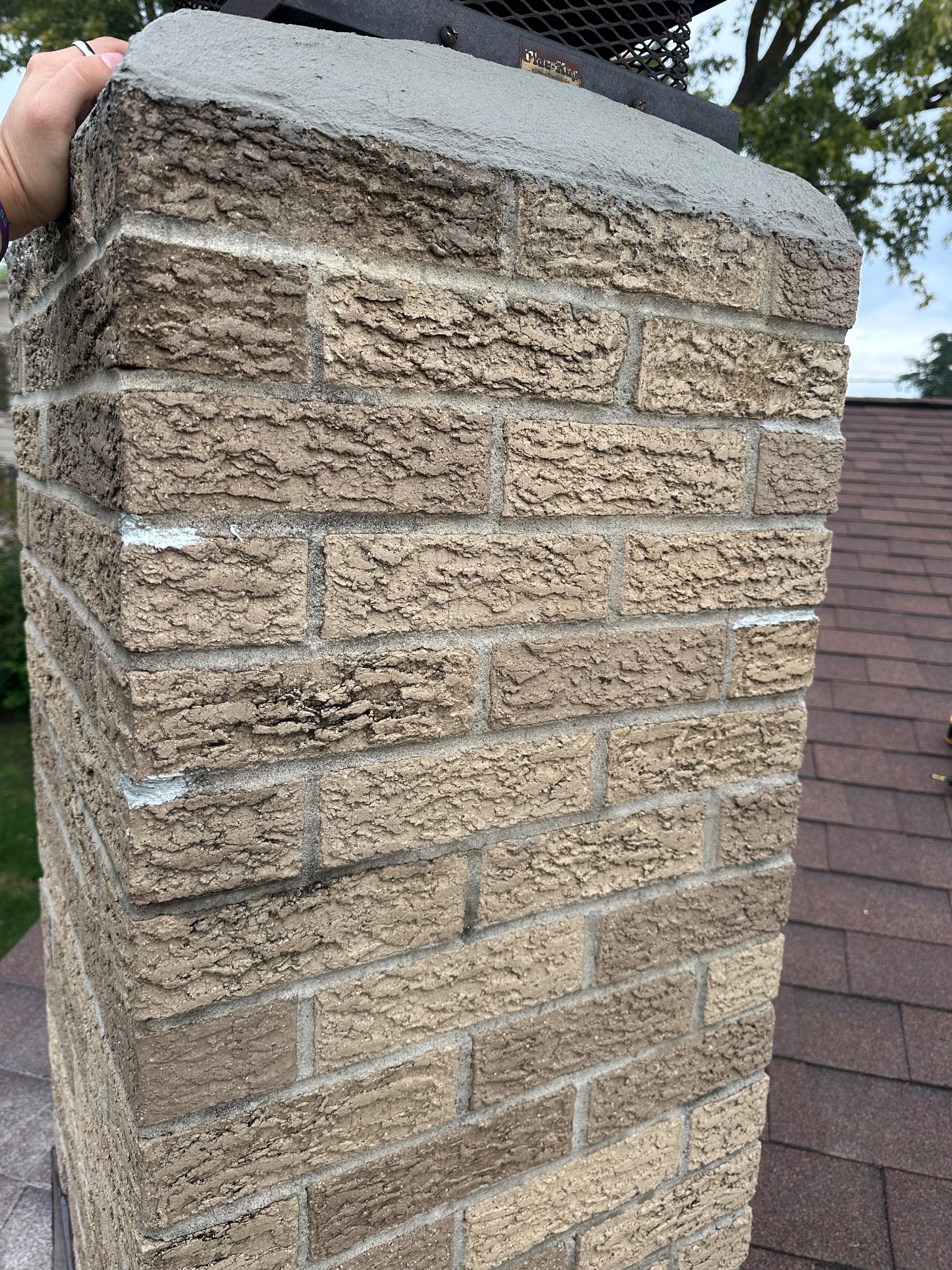 Top of chimney with sealed cap and mortar joints on a roof in Ames handyman project.