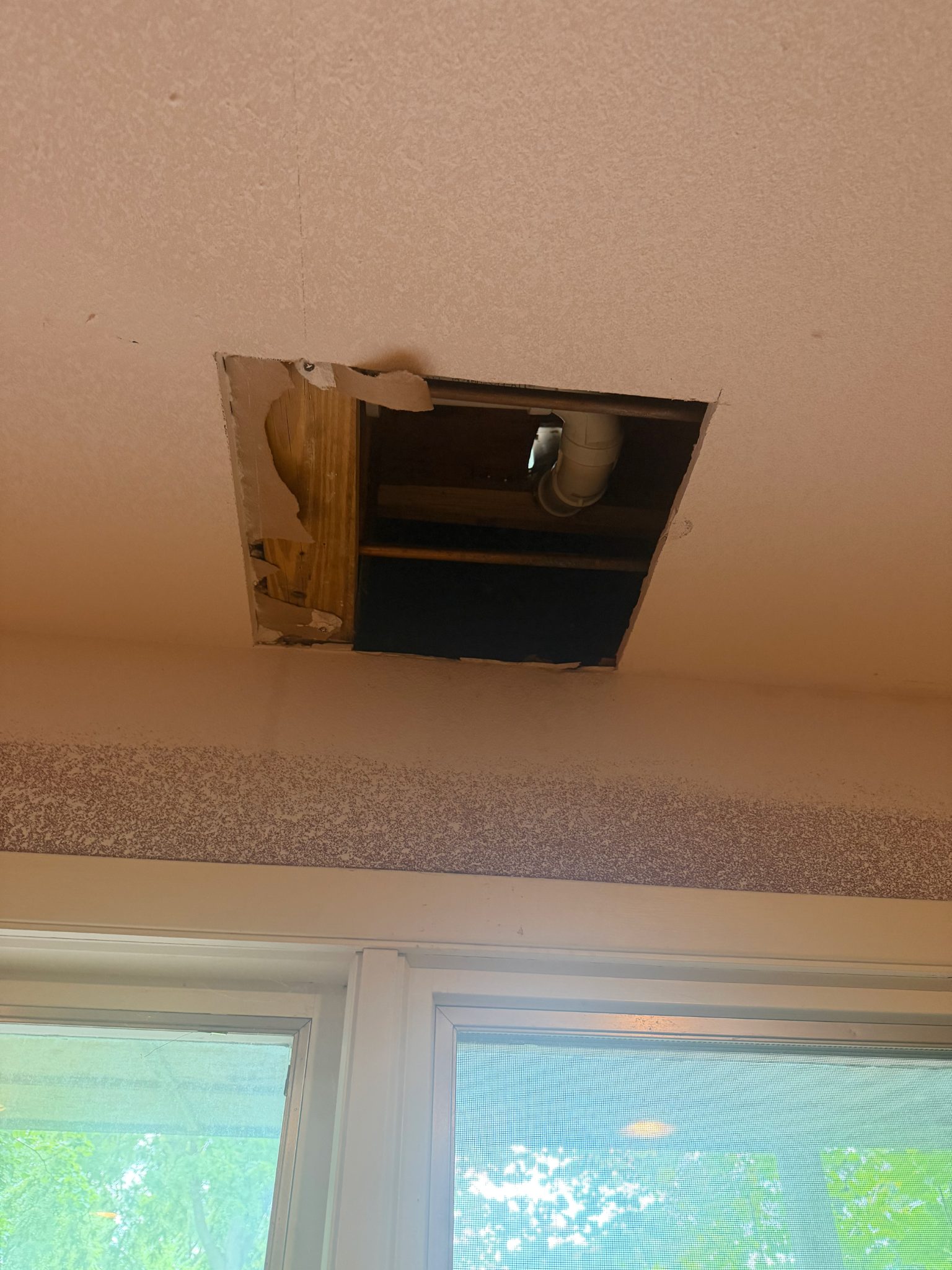 Ceiling drywall opening with visible piping in Ames, handyman project.